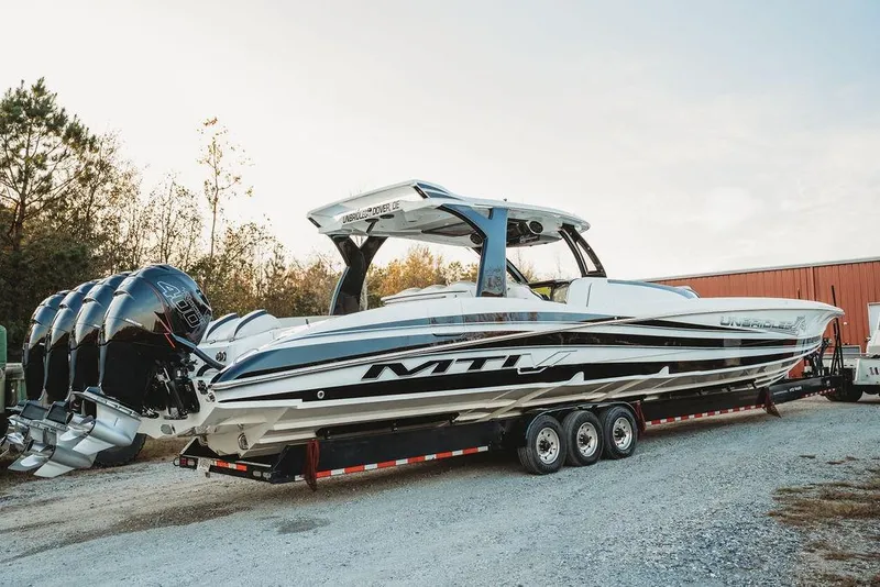 Slide: The Image of 2018 MTI 57 boat on trailer with four powerful outboard engines, parked outdoors. - 1