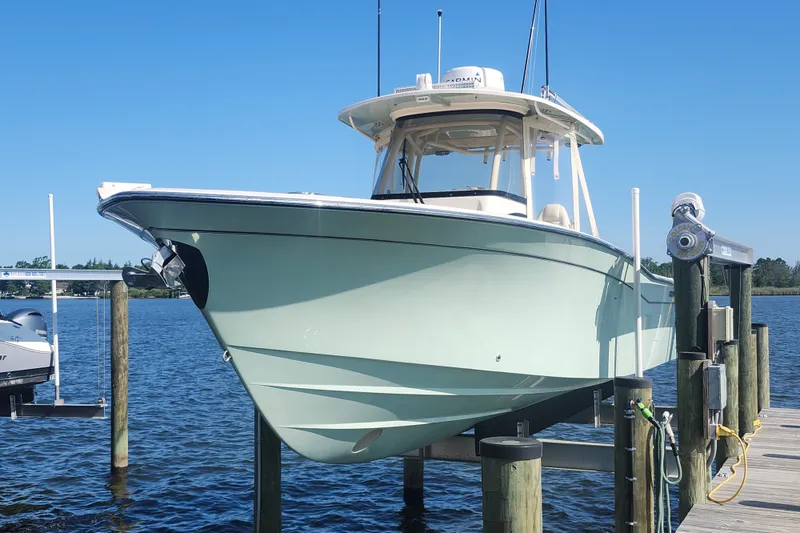 Slide: The Image of 2021 Grady-White Canyon 306 boat docked on a lift, clear blue sky background. - 1