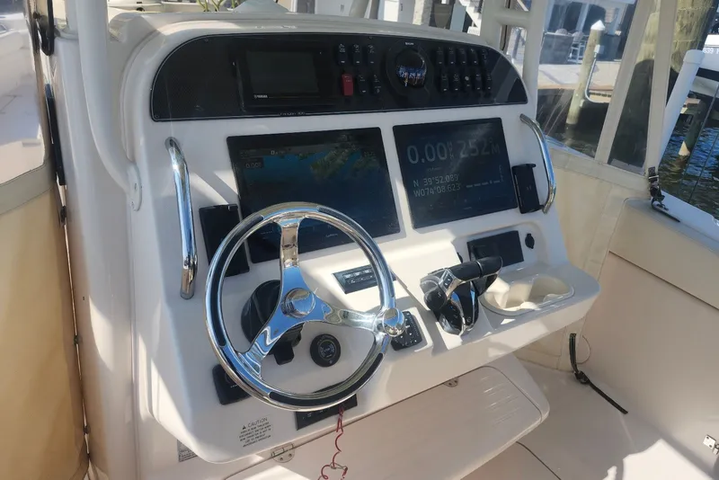 Slide: The Image of 2021 Grady-White Canyon 306 boat dashboard with steering wheel and navigation controls. - 13
