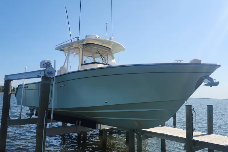 Slide: The Image of 2021 Grady-White Canyon 306 boat docked on a lift, clear blue sky background. - 2