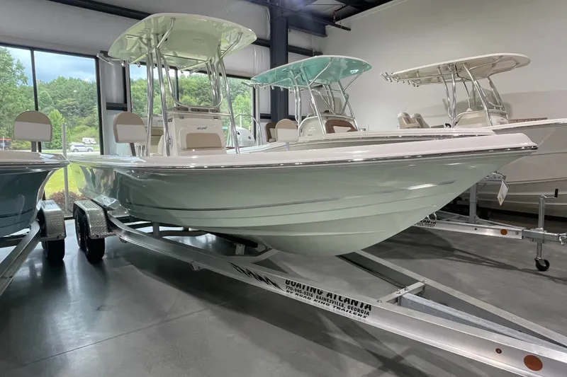 Slide: The Image of 2026 Bulls Bay 2400 boat on trailer in showroom, featuring sleek design and T-top canopy. - 1
