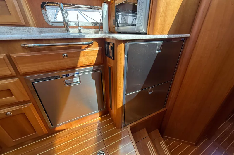 Slide: The Image of Luxurious 2018 Sabre 45 Salon Express yacht kitchen with wood cabinetry and stainless steel appliances. - 52