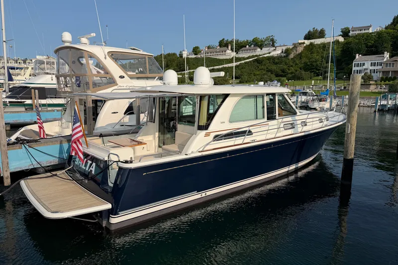 The Image of 2018 Sabre 45 Salon Express yacht docked in a marina, featuring sleek design and American flag. - 0