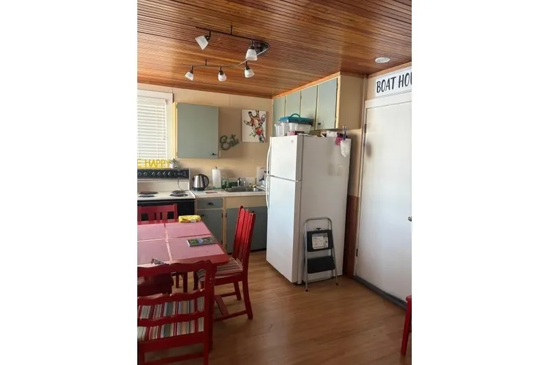 Slide: The Image of Cozy boathouse kitchen with wooden ceiling, red chairs, and white appliances. - 7
