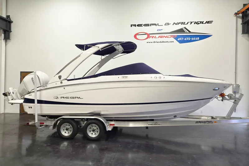 The Image of 2027 Regal LX4 boat on trailer in showroom, featuring sleek design and Yamaha outboard motor. - 1