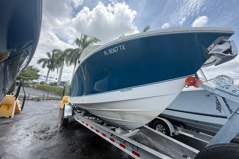 Slide: The Image of 2025 Regulator 25 boat on trailer, parked outdoors under cloudy sky. - 12