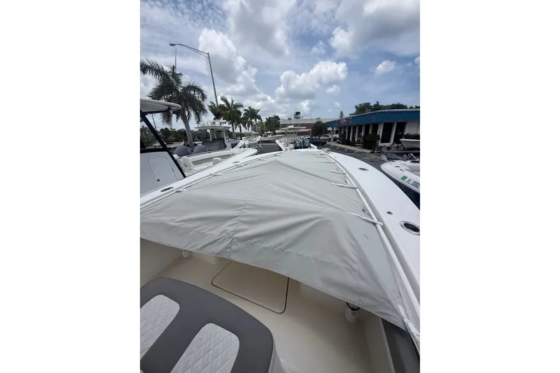 Slide: The Image of 2025 Regulator 25 boat with covered deck, parked at a marina under a cloudy sky. - 24
