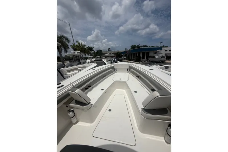 Slide: The Image of 2025 Regulator 25 boat deck with seating, under a cloudy sky at a marina. - 22