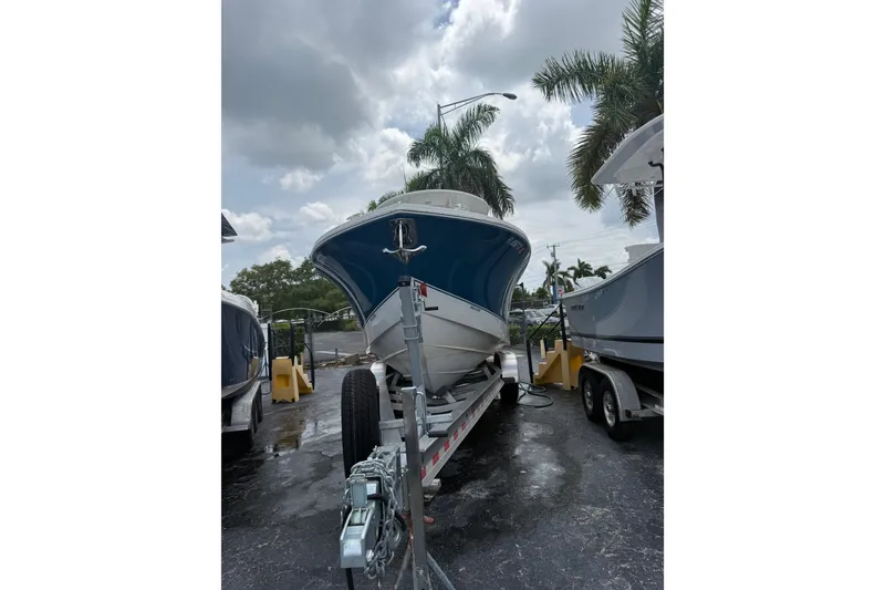Slide: The Image of 2025 Regulator 25 boat on trailer under cloudy sky with palm trees. - 13