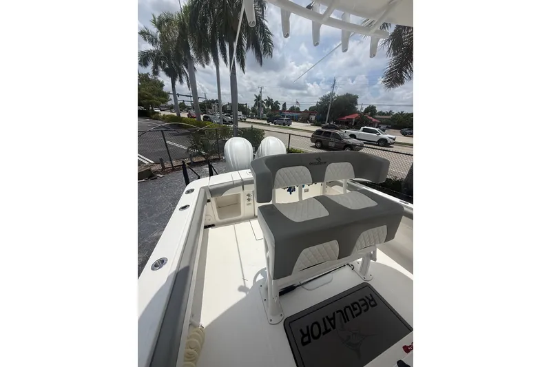 Slide: The Image of 2025 Regulator 25 boat interior with seating, palm trees, and parked cars in the background. - 18
