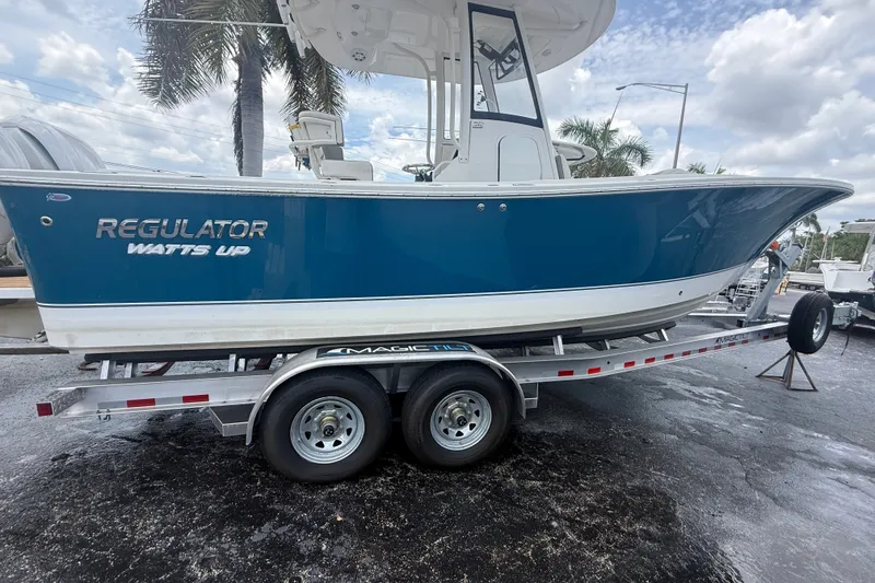 Slide: The Image of 2025 Regulator 25 boat on trailer, blue hull, palm trees in background. - 5