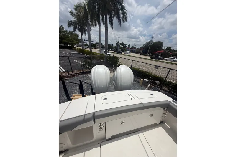 Slide: The Image of 2025 Regulator 25 boat with dual engines, parked near palm trees and a road. - 19