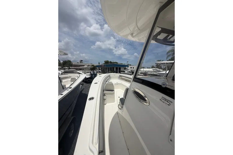 Slide: The Image of 2025 Regulator 25 boat, sleek design, parked outdoors under a partly cloudy sky. - 20