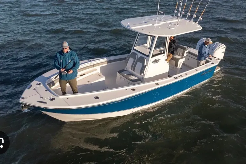 Slide: The Image of 2025 Regulator 25 boat on water with people fishing, featuring blue and white design. - 3