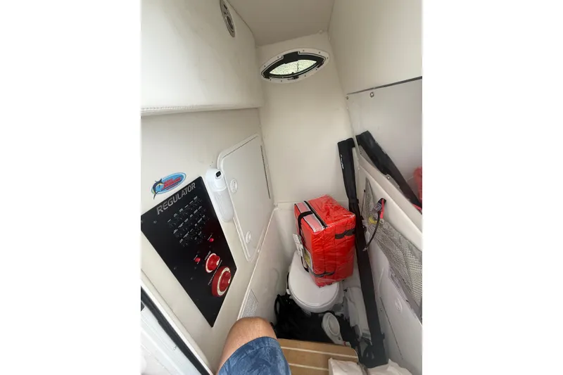 Slide: The Image of Interior of 2025 Regulator 25 boat featuring control panel and compact toilet area. - 14