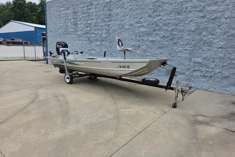 Slide: The Image of 1997 Lowe Bass Striker 170 boat on trailer, parked outdoors near a blue building. - 3