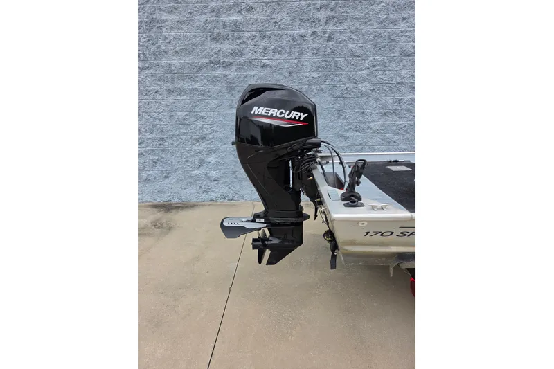 Slide: The Image of 1997 Lowe Bass Striker 170 with Mercury outboard motor, parked on concrete. - 4