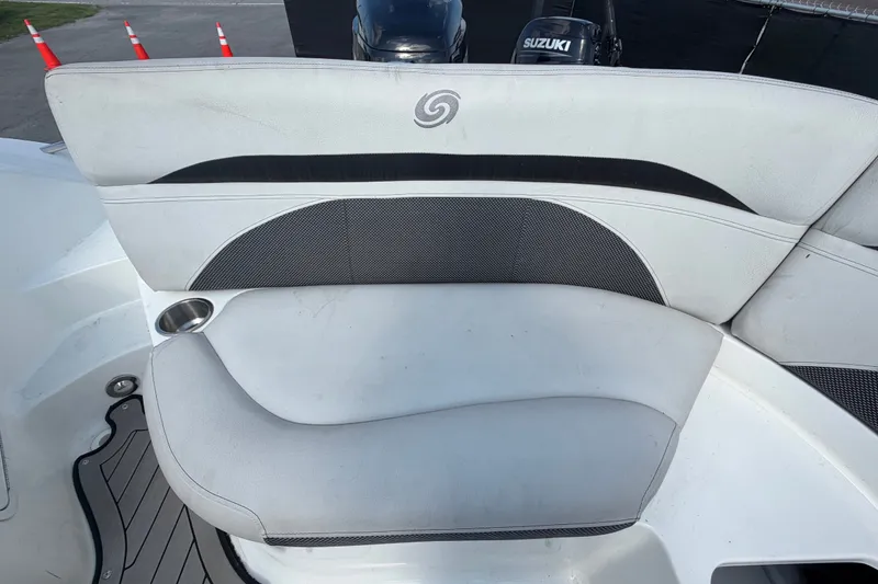 Slide: The Image of 2019 Hurricane SunDeck 2400 OB boat seating with cup holder and Suzuki engine in background. - 67