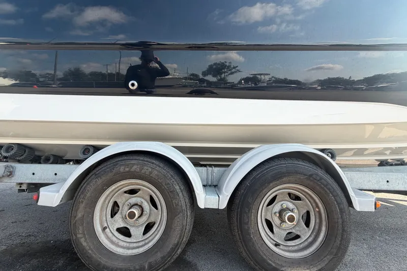 Slide: The Image of 2019 Hurricane SunDeck 2400 OB boat on trailer, showcasing dual wheels and sleek hull design. - 81