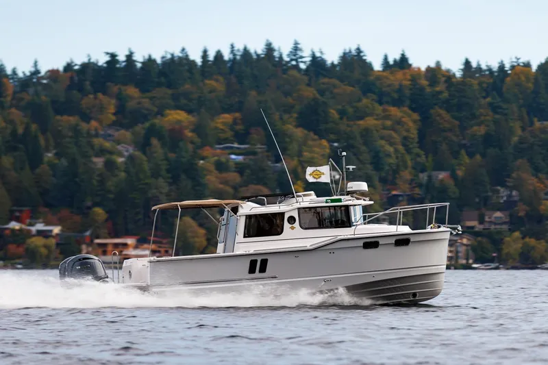 The Image of 2026 Ranger Tugs R-27 cruising on a scenic lake with forested background. - 2