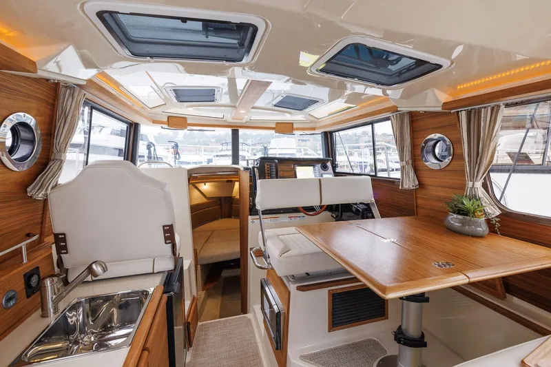 Slide: The Image of 2026 Ranger Tugs R-27 interior with wood accents, dining area, and modern amenities. - 20