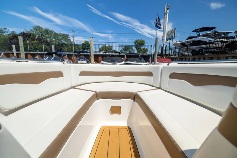 Slide: The Image of 2015 Chaparral 246 SSi boat interior with white and tan seating, docked under a clear blue sky. - 19