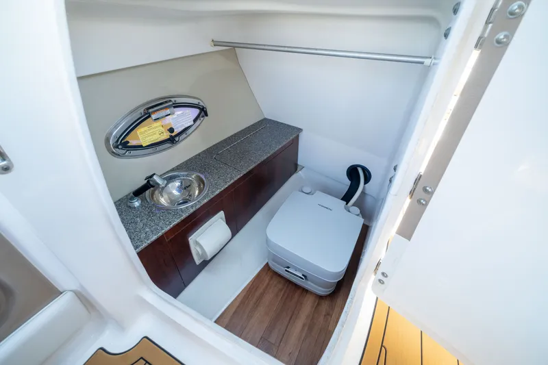 Slide: The Image of 2015 Chaparral 246 SSi boat interior with compact bathroom, sink, and toilet. - 16