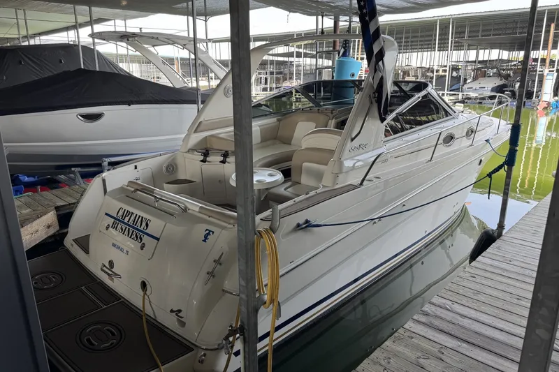 Slide: The Image of 2000 Sea Ray 290 Sundancer docked in a marina, featuring spacious seating and sleek design. - 2
