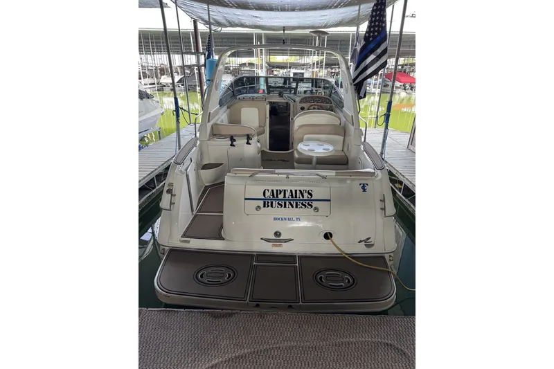 Slide: The Image of 2000 Sea Ray 290 Sundancer boat docked, rear view with seating and flag. - 3