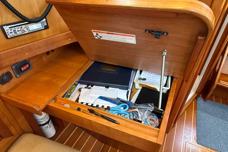 Slide: The Image of Wooden navigation desk with open drawer, containing various items, aboard a 2009 Sabre 386 sailboat. - 17