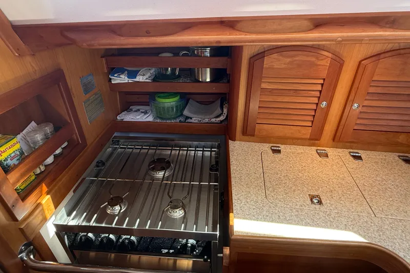 Slide: The Image of 2009 Sabre 386 yacht kitchen with stove, wooden cabinets, and storage shelves. - 30