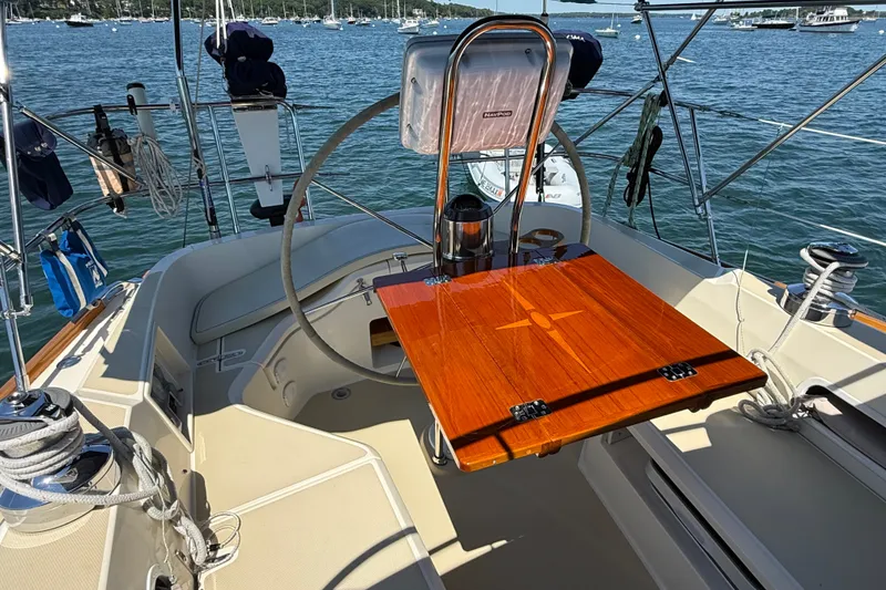 Slide: The Image of Cockpit of 2009 Sabre 386 sailboat with wooden table and steering wheel, docked on calm water. - 77
