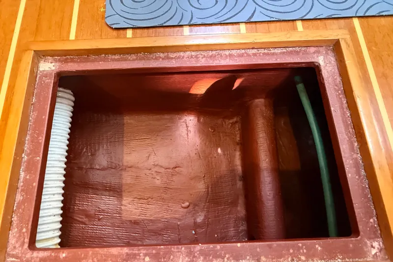 Slide: The Image of Open compartment in 2009 Sabre 386 boat with visible hoses and wooden trim. - 105