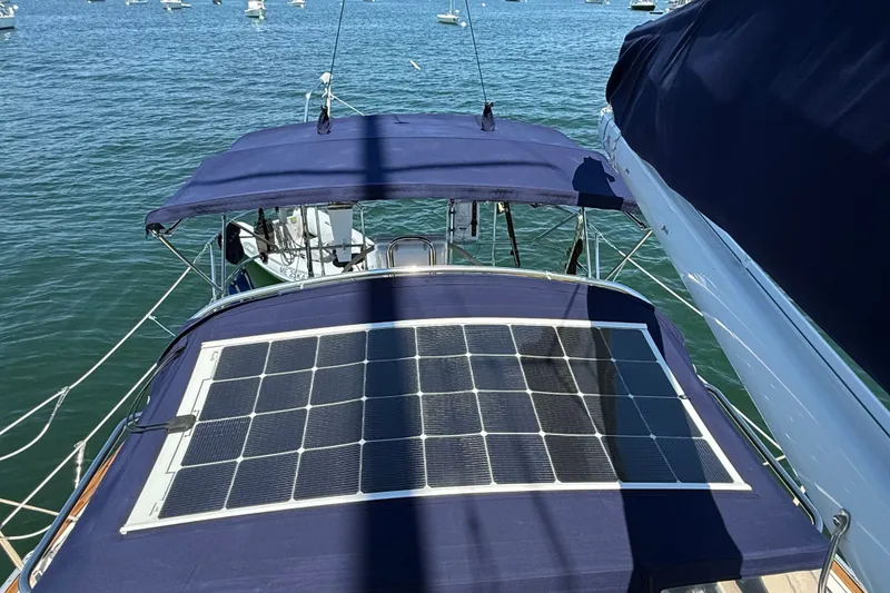 Slide: The Image of Sailboat Sabre 386 (2009) with solar panels on deck, anchored in a serene bay. - 102