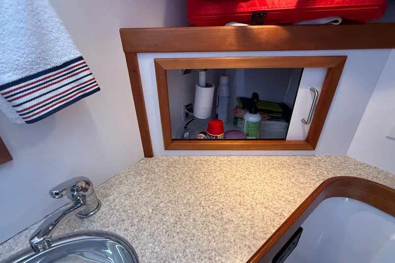 Slide: The Image of Bathroom cabinet in a 2009 Sabre 386 yacht, featuring toiletries and a towel. - 52
