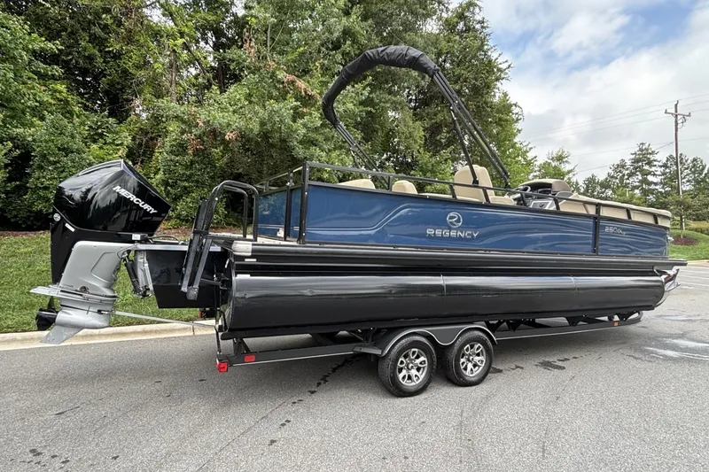 Slide: The Image of 2025 Regency 250DL3 pontoon boat on trailer, parked outdoors. - 14