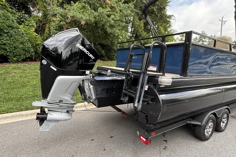 Slide: The Image of 2025 Regency 250DL3 pontoon boat with Mercury outboard motor on a trailer. - 15