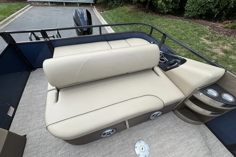 Slide: The Image of 2025 Regency 250DL3 pontoon boat interior with beige seating and cup holders. - 21