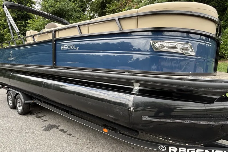 Slide: The Image of 2025 Regency 250DL3 pontoon boat on trailer, featuring sleek blue and black design. - 16