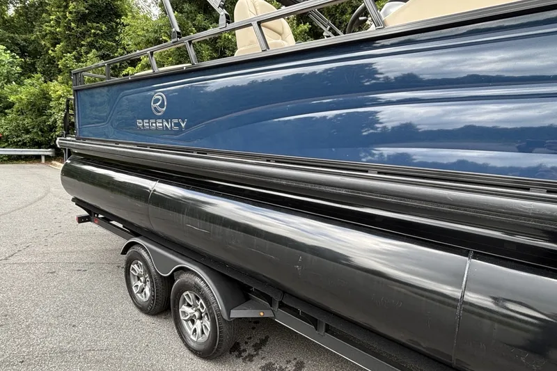 Slide: The Image of 2025 Regency 250DL3 pontoon boat on trailer, featuring sleek design and dual axles. - 17