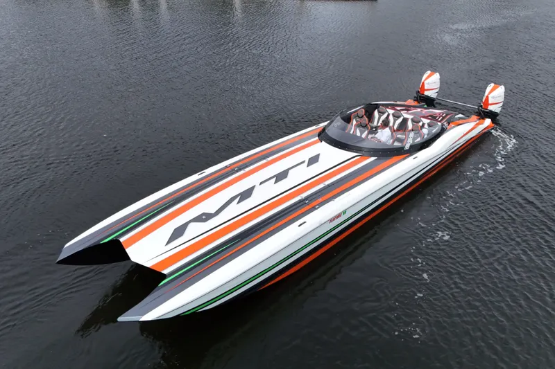 Slide: The Image of 2024 MTI 440X powerboat with vibrant orange and black stripes on calm water. - 1