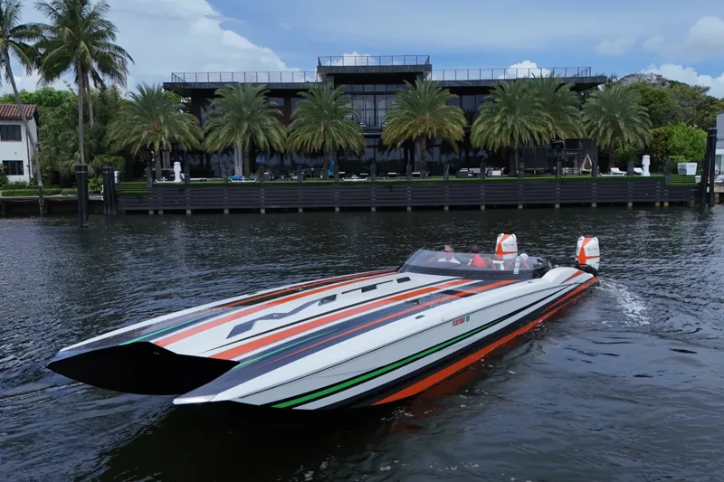 Slide: The Image of 2024 MTI 440X powerboat cruising on water near luxury waterfront homes. - 6