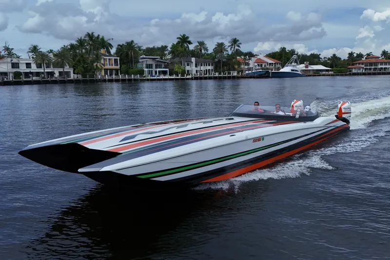 Slide: The Image of 2024 MTI 440X speedboat cruising on a scenic waterway with luxury homes in the background. - 2