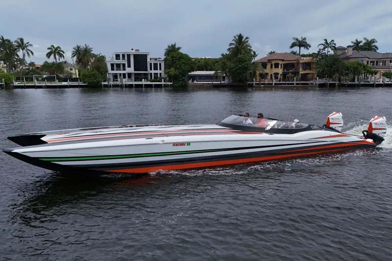 The Image of 2024 MTI 440X powerboat cruising on a scenic waterway with luxury homes in the background. - 3