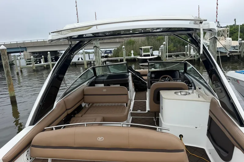 Slide: The Image of 2020 Cobalt 30SC boat interior with brown seating, docked near a bridge. - 23
