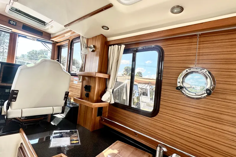 Slide: The Image of Interior of 2026 Ranger Tugs R-31 CB with wood paneling and porthole window. - 7