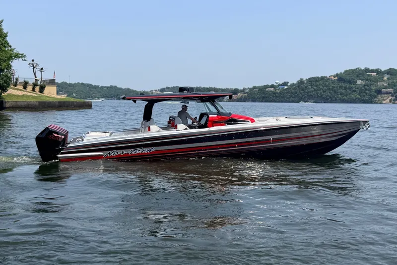 Slide: The Image of 2027 Nor-Tech 42 Eleven boat cruising on a scenic lake with lush green hills. - 11