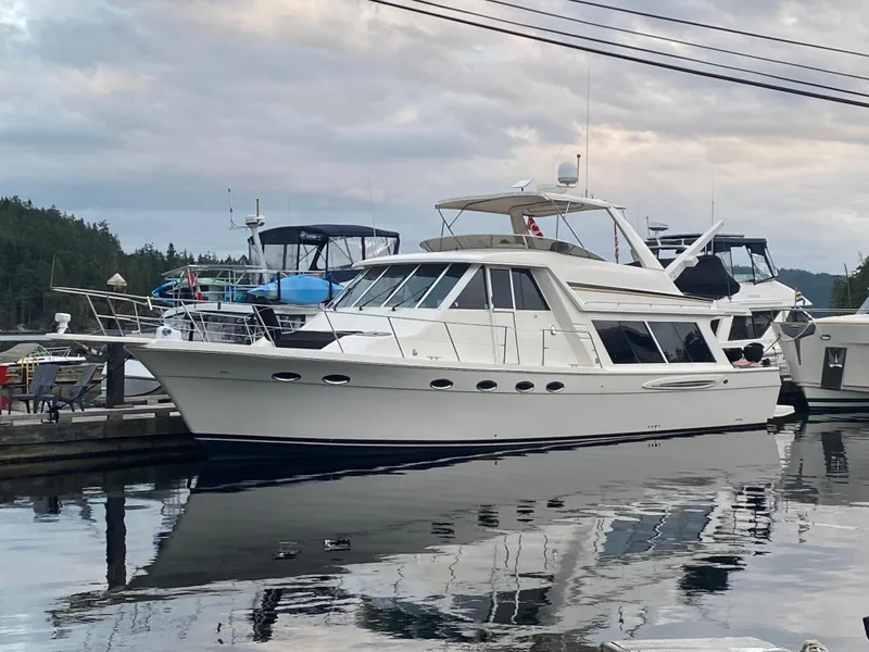 Slide: The Image of 2003 Meridian 490 Pilothouse yacht docked at a marina, reflecting on calm water. - 1