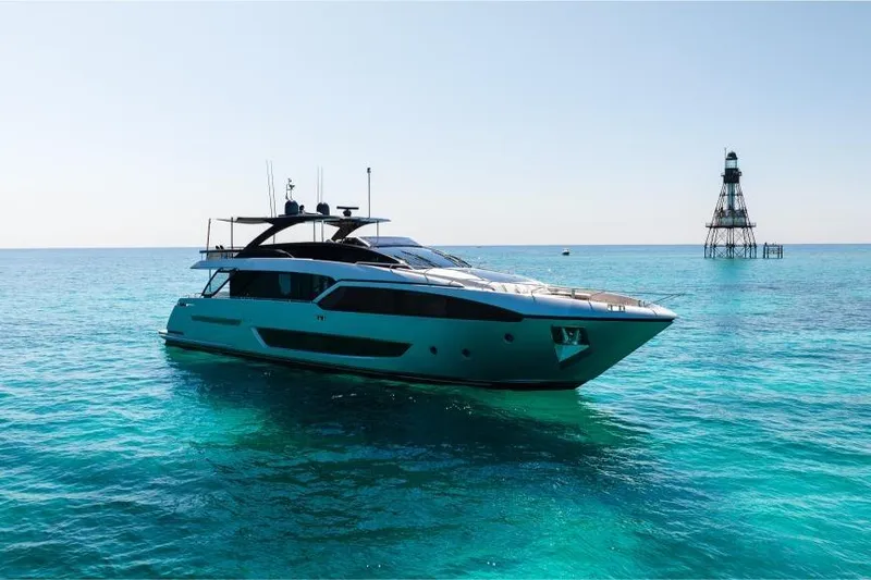 The Image of Luxury 2022 Riva 90' Argo yacht on clear turquoise waters near a lighthouse. - 0