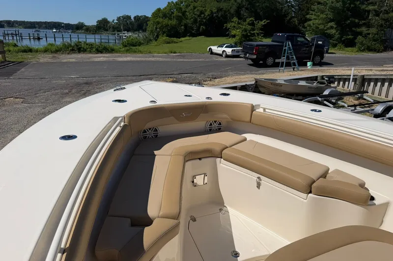 Slide: The Image of 2019 Scout 300 LXF boat with tan seating, docked near a scenic waterfront. - 22